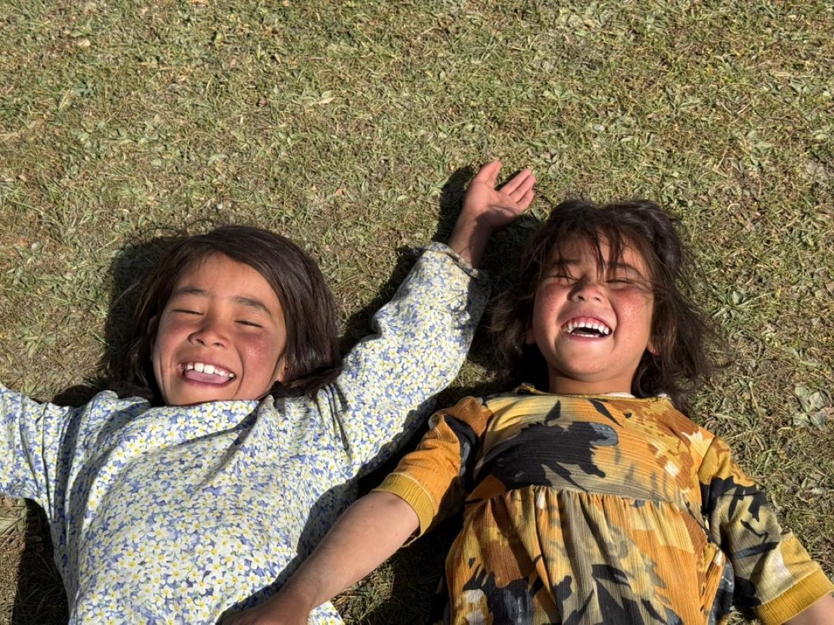 Two children laughing together on the grass