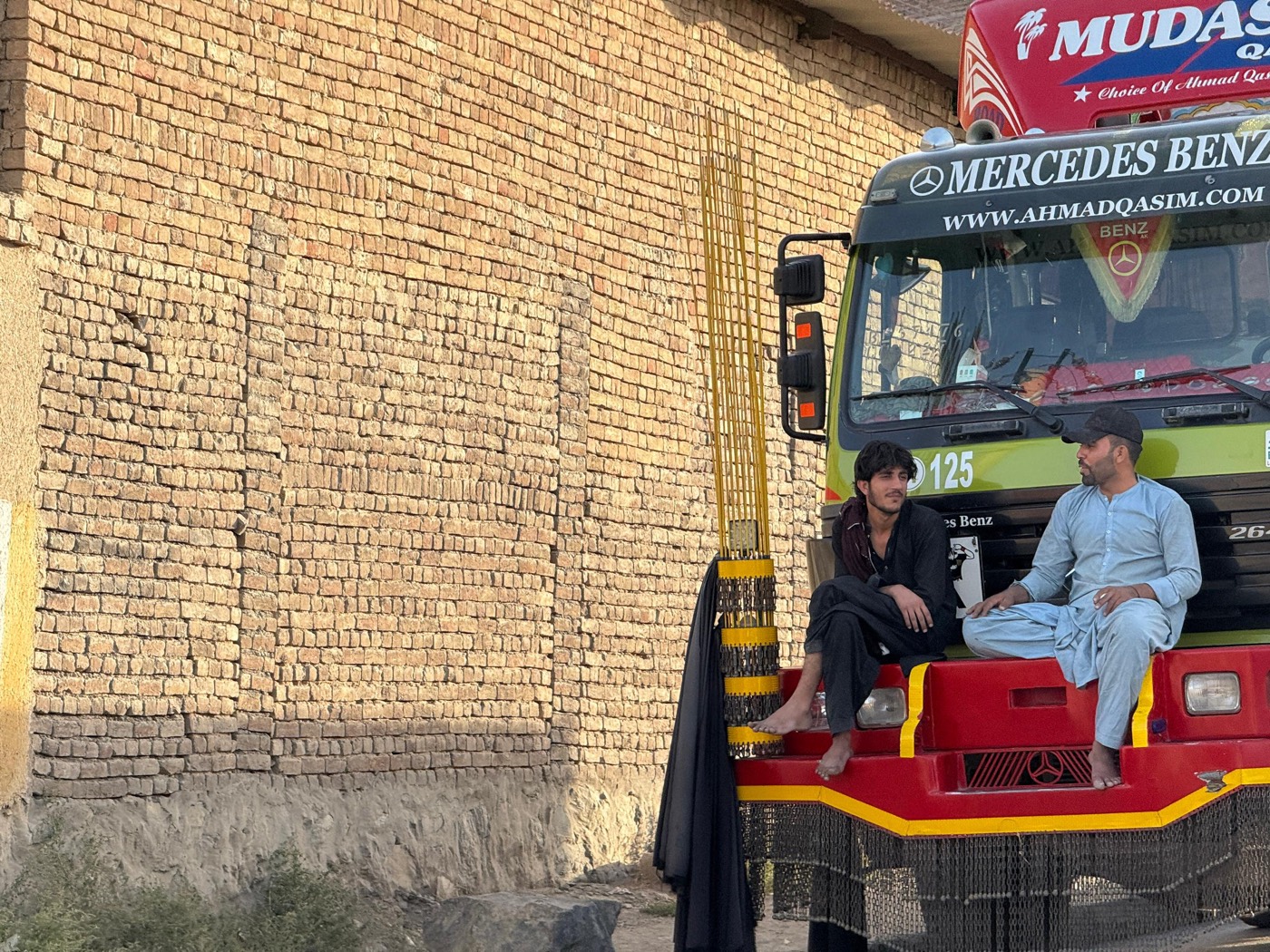 A brightly decorated Afghan truck parked by a brick wall